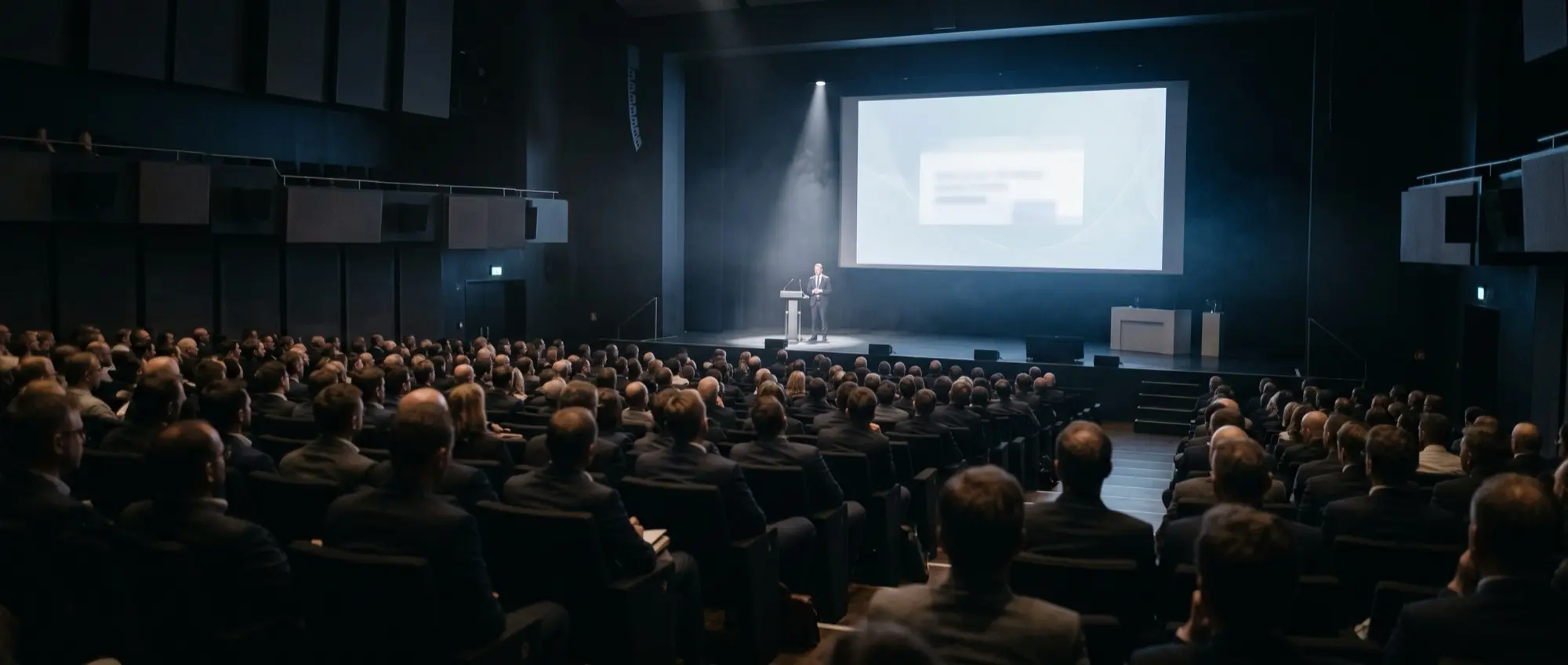 A keynote hall during a talk, audience in soft darkness